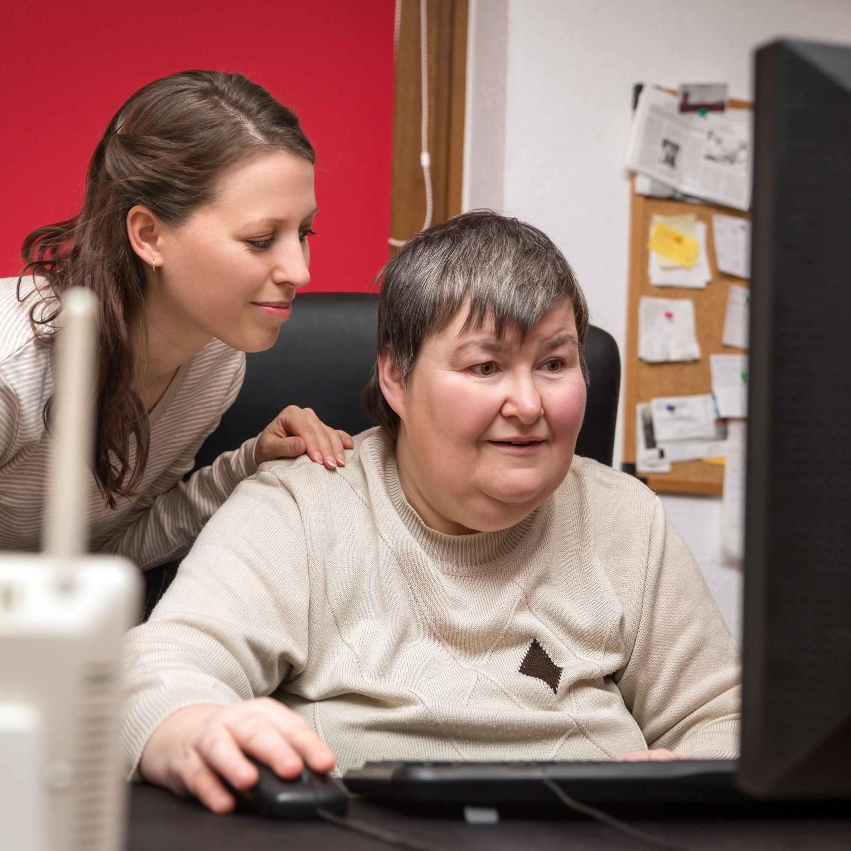 Woman with disability learning to use assistive technology software and computer with UCP staff member.