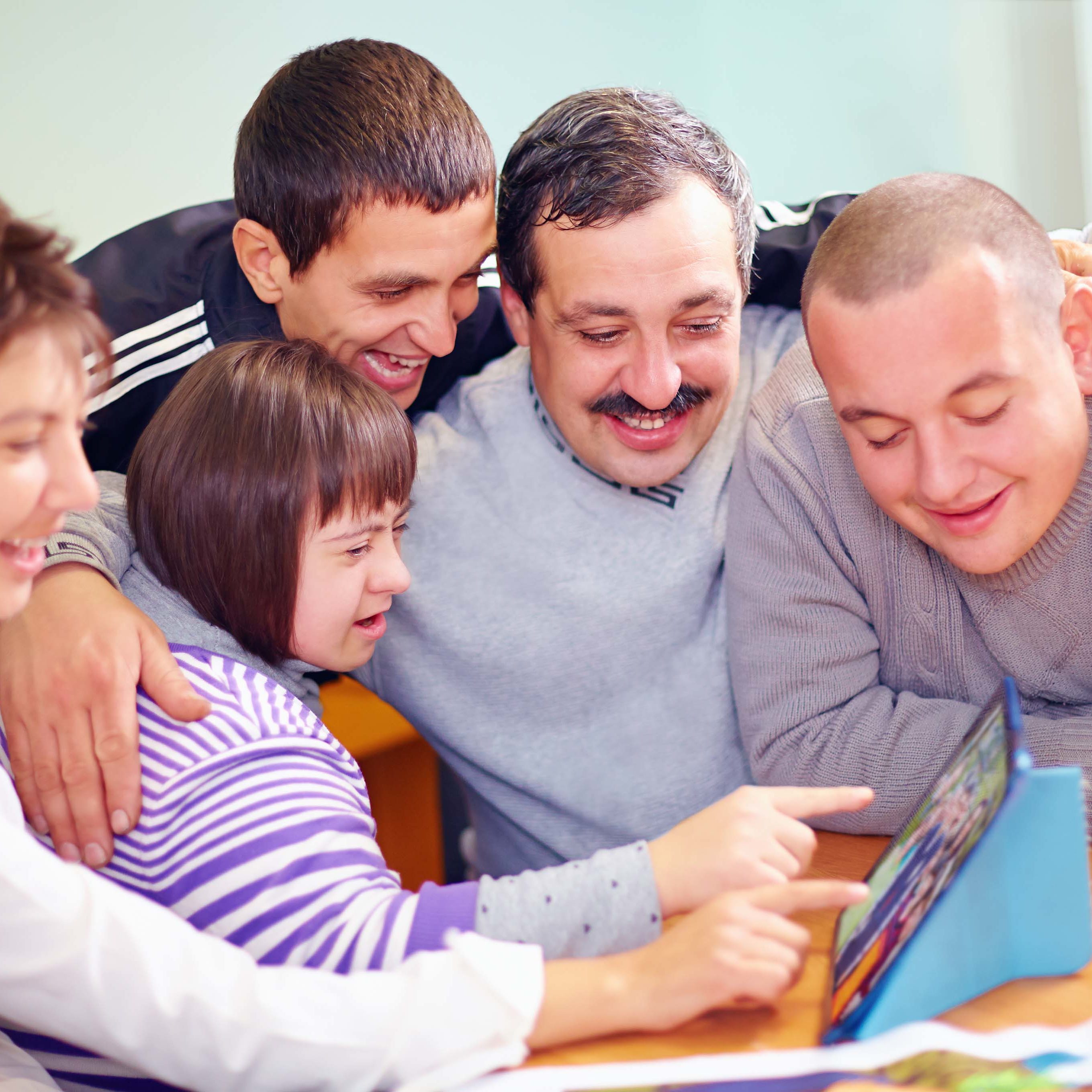 group of happy people with disability having fun with tablet Family using assistive technology tablet disabled daughter.