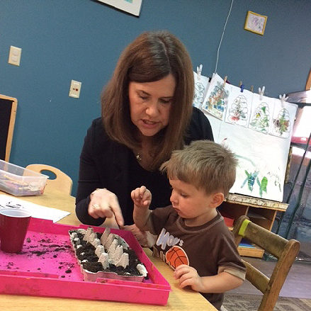 UCP Staff member teaching a child with disabilities about plants in a classroom setting.
